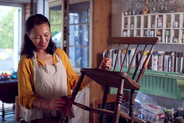 Mujer terminando restaurar silla madera